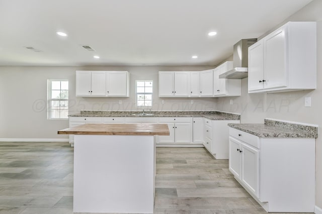 918 N Gray St, Amarillo, TX 79065 - kitchen with wall chimney exhaust hood, a center island, recessed lighting, white cabinetry, and light wood-type flooring