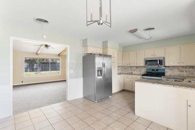 5003 Greenway Pl, Amarillo, TX 79109 - kitchen featuring stainless steel appliances, cream cabinets, light carpet, a ceiling fan, and decorative backsplash