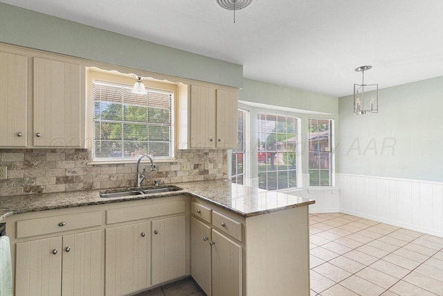 5003 Greenway Pl, Amarillo, TX 79109 - kitchen with a peninsula, a wainscoted wall, decorative backsplash, hanging light fixtures, and light stone countertops