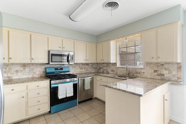 5003 Greenway Pl, Amarillo, TX 79109 - kitchen with appliances with stainless steel finishes, cream cabinets, a peninsula, and backsplash