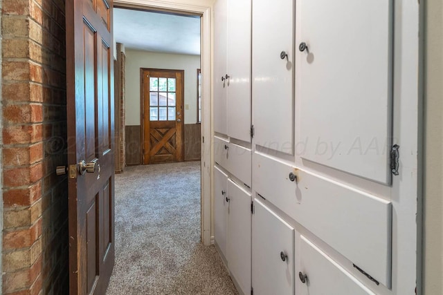 hallway featuring light carpet and wainscoting
