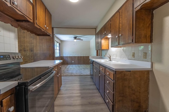 kitchen with stainless steel electric range, a ceiling fan, wood finished floors, a sink, and light countertops