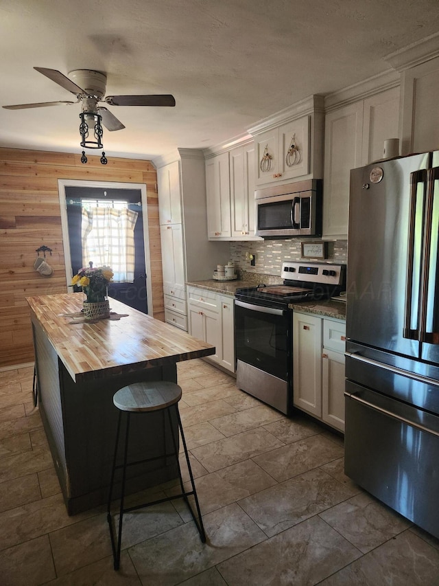 3114 Palm St, Amarillo, TX 79107 - kitchen featuring appliances with stainless steel finishes, wooden counters, tasteful backsplash, a ceiling fan, and wooden walls