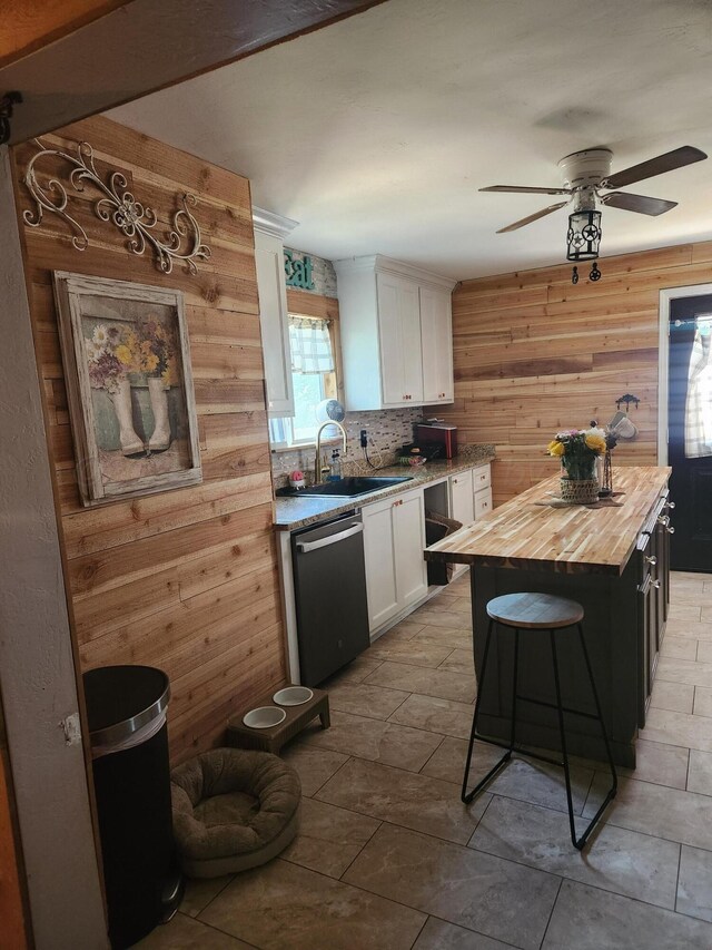 3114 Palm St, Amarillo, TX 79107 - kitchen featuring wooden counters, dishwashing machine, white cabinets, wood walls, and a ceiling fan