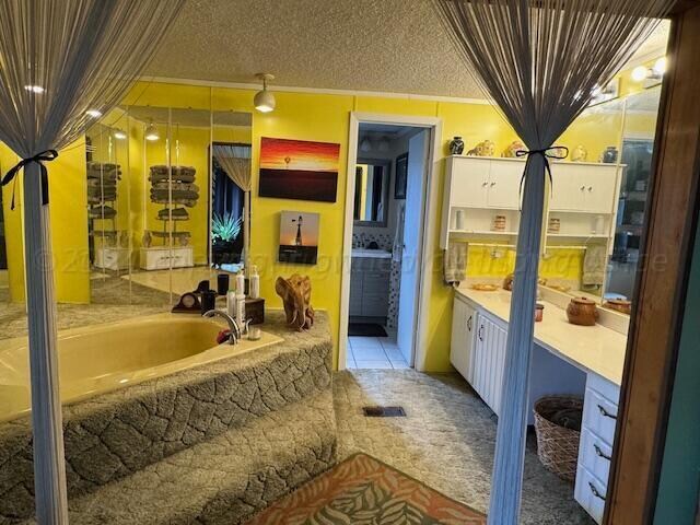 bathroom with ornamental molding, tile patterned flooring, a bathtub, and a textured ceiling