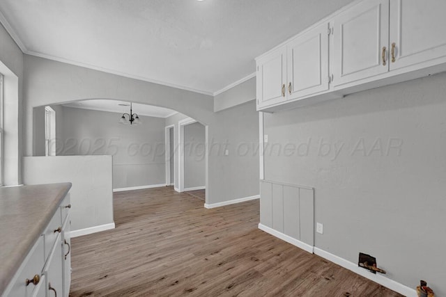 4360 S Polk St, Amarillo, TX 79110 - empty room with crown molding, light wood-type flooring, arched walkways, and a chandelier