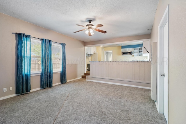 unfurnished living room with carpet floors, a textured ceiling, and ceiling fan