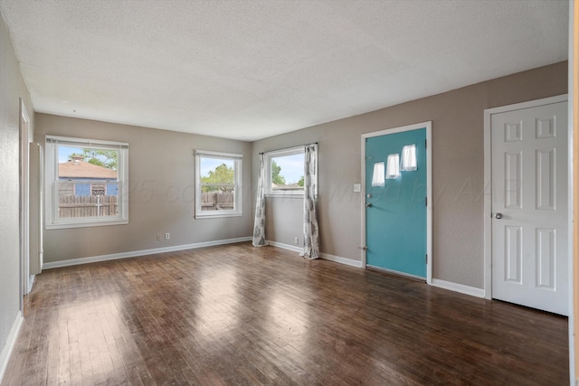 unfurnished living room with a textured ceiling, baseboards, and wood finished floors