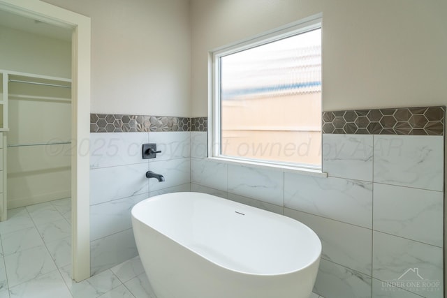 1207 Herring Ranch Rd, Amarillo, TX 79124 - full bathroom featuring tile walls, a soaking tub, marble look tile flooring, and wainscoting