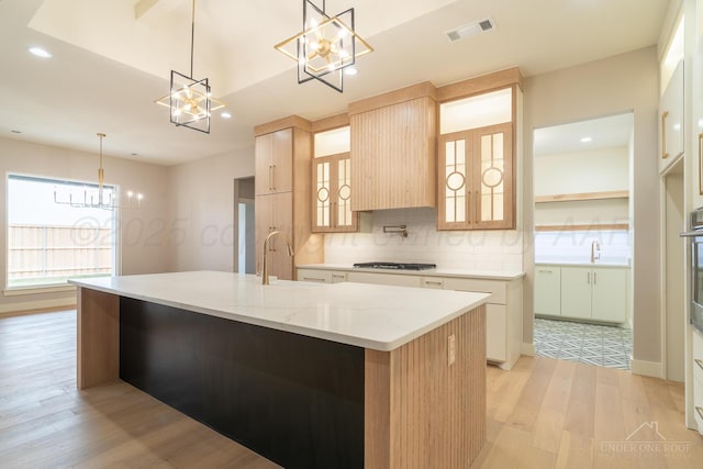 1207 Herring Ranch Rd, Amarillo, TX 79124 - kitchen with a chandelier, light wood finished floors, stainless steel appliances, tasteful backsplash, and a spacious island