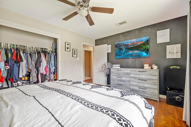 bedroom with a closet, wood finished floors, a ceiling fan, and baseboards