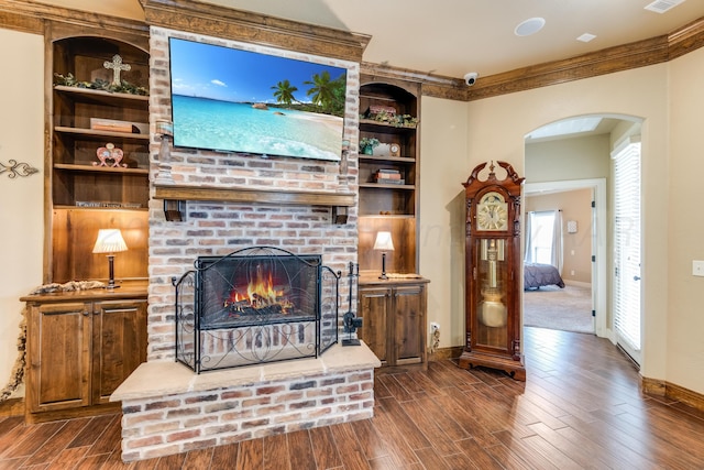 12 William Ln, Canyon, TX 79015 - living room with arched walkways, dark wood-style flooring, a brick fireplace, built in features, and ornamental molding