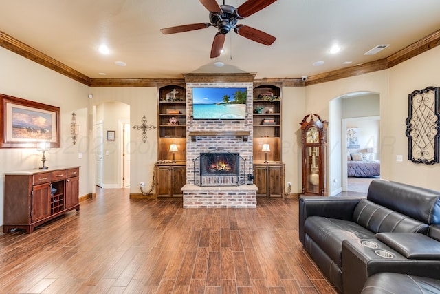 12 William Ln, Canyon, TX 79015 - living room with arched walkways, crown molding, ceiling fan, dark wood-type flooring, and a brick fireplace