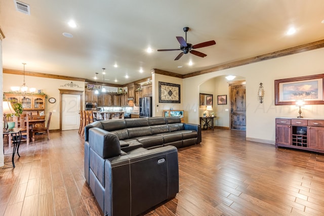 12 William Ln, Canyon, TX 79015 - living area with arched walkways, a ceiling fan, crown molding, wood finished floors, and a chandelier