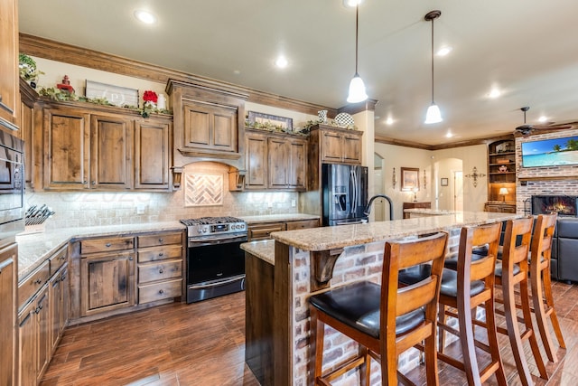 12 William Ln, Canyon, TX 79015 - kitchen featuring black fridge, stainless steel gas stove, crown molding, an island with sink, and dark wood-style flooring