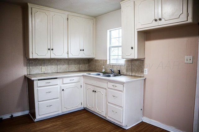 kitchen featuring dark hardwood / wood-style flooring, backsplash, sink, and white cabinets