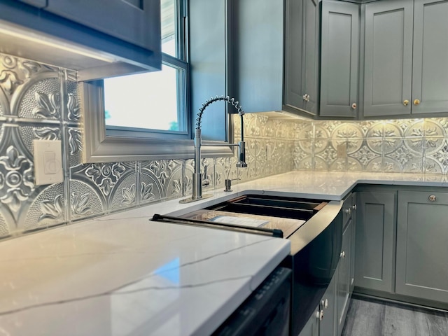 kitchen with gray cabinetry, light stone countertops, tasteful backsplash, and hardwood / wood-style floors