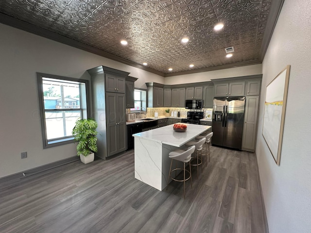 kitchen with dark wood-type flooring, plenty of natural light, appliances with stainless steel finishes, and a center island