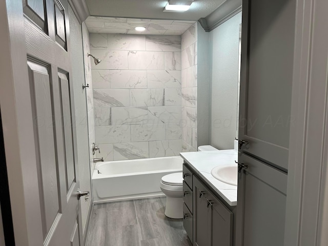 full bathroom with vanity, a textured ceiling, tiled shower / bath combo, hardwood / wood-style floors, and toilet