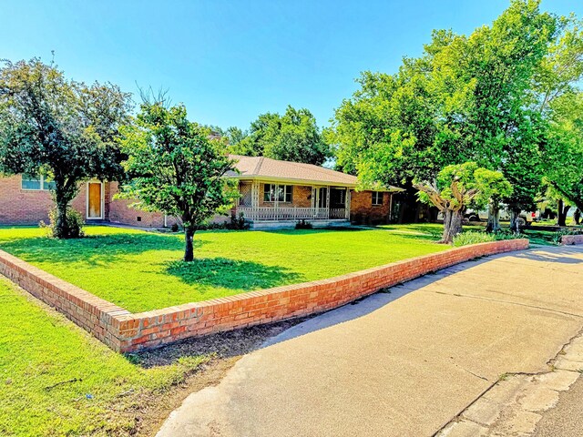 1301 S Fordham St, Perryton, TX 79070 - view of front of home featuring a front yard, brick siding, and covered porch