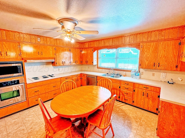 1301 S Fordham St, Perryton, TX 79070 - kitchen with stainless steel appliances, ceiling fan, light countertops, brown cabinetry, and a textured ceiling