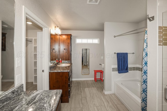 3001 Bismarck Ave, Amarillo, TX 79118 - bathroom with vanity, a bathtub, curtained shower, a spacious closet, and baseboards