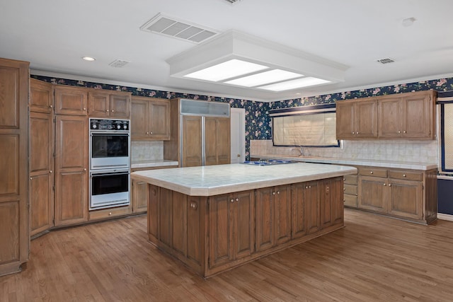 2614 Parker St, Amarillo, TX 79109 - kitchen featuring white double oven, tile countertops, paneled fridge, light wood finished floors, and a center island
