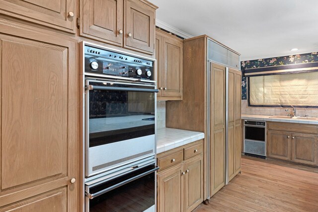 2614 Parker St, Amarillo, TX 79109 - kitchen with a sink, tile counters, light wood-type flooring, and decorative backsplash