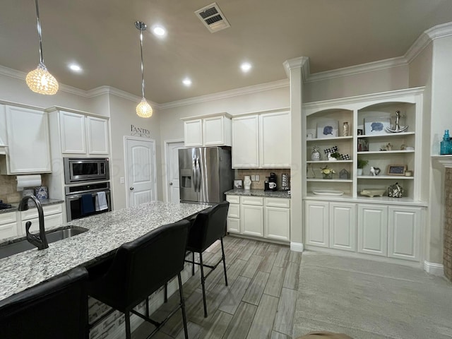 kitchen featuring appliances with stainless steel finishes, light stone counters, visible vents, and a sink