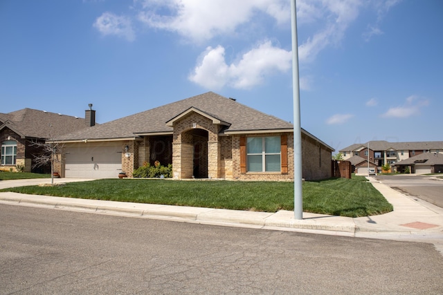 ranch-style house with driveway, a shingled roof, an attached garage, brick siding, and a front lawn