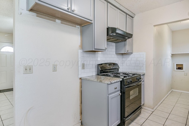 1736 Jennifer St, Amarillo, TX 79107 - kitchen featuring black gas range, under cabinet range hood, gray cabinetry, backsplash, and light tile patterned flooring