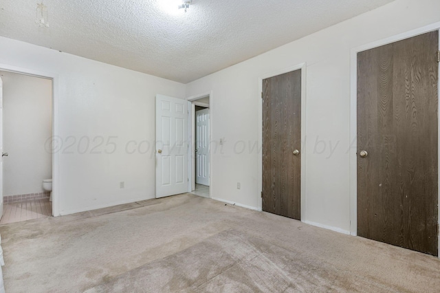 1736 Jennifer St, Amarillo, TX 79107 - unfurnished bedroom with carpet flooring, two closets, connected bathroom, and a textured ceiling