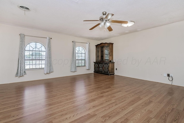 1736 Jennifer St, Amarillo, TX 79107 - unfurnished living room with wood finished floors, healthy amount of natural light, a ceiling fan, and a textured ceiling