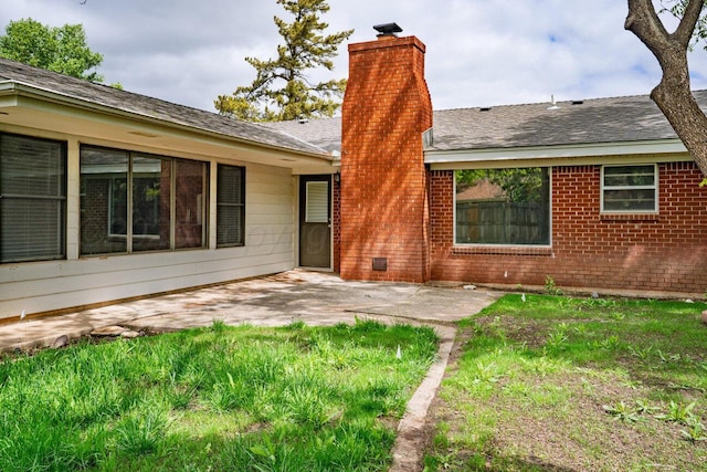 back of house with a patio area, a chimney, brick siding, and a shingled roof