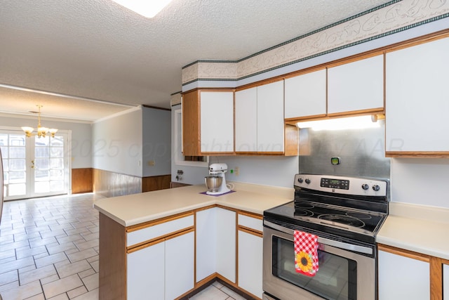 kitchen with a peninsula, stainless steel range with electric cooktop, a textured ceiling, and light countertops