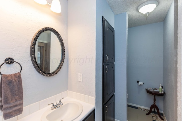 bathroom with tile patterned flooring, vanity, and a textured ceiling