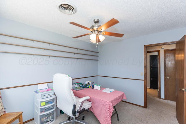 office space featuring a ceiling fan, a textured ceiling, light colored carpet, baseboards, and visible vents