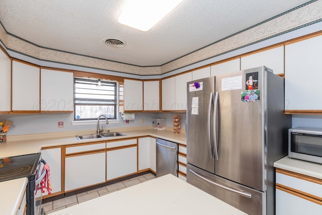 kitchen with stainless steel appliances, light countertops, visible vents, a sink, and a textured ceiling