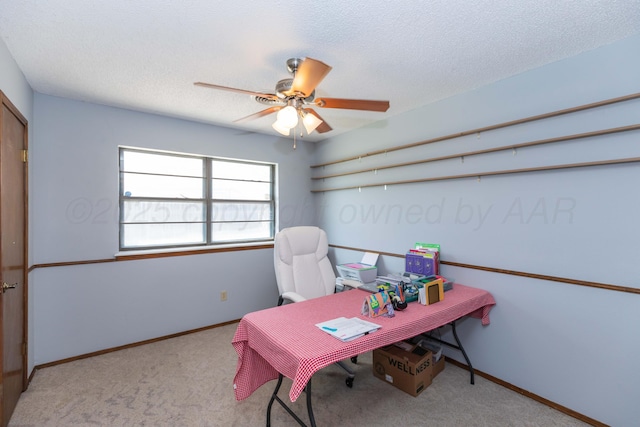 carpeted home office with baseboards and a ceiling fan
