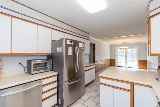 kitchen featuring a toaster, stainless steel appliances, light countertops, white cabinets, and a notable chandelier