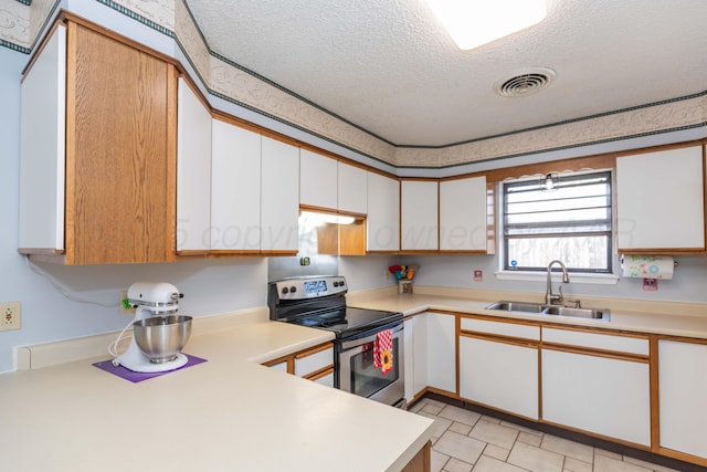 kitchen with a sink, a textured ceiling, stainless steel range with electric cooktop, visible vents, and light countertops
