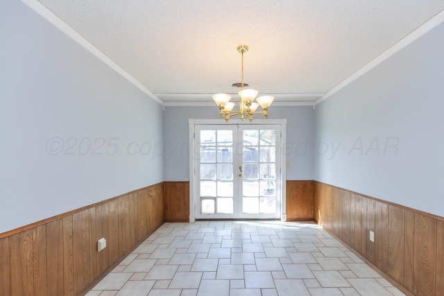 unfurnished dining area with wainscoting, wood walls, and a notable chandelier