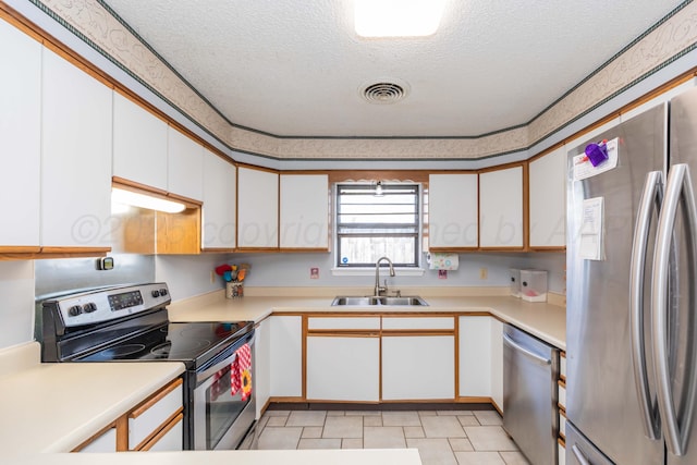kitchen featuring a textured ceiling, a sink, stainless steel appliances, light countertops, and visible vents