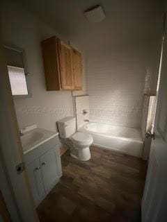 5218 Slope Dr, Amarillo, TX 79108 - bathroom with vanity, toilet, wood finished floors, and shower / bath combination