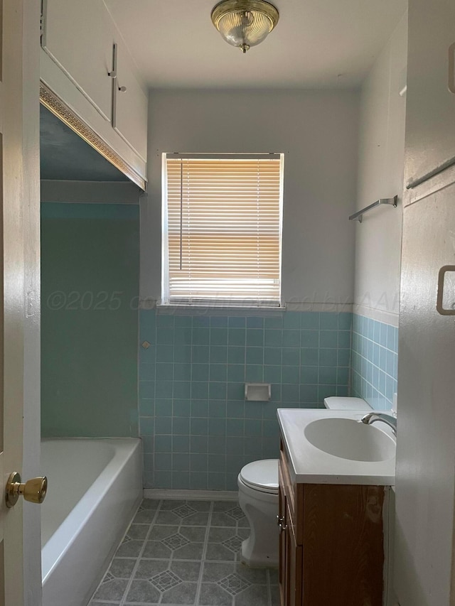 full bath featuring toilet, a wainscoted wall, tile patterned flooring, vanity, and tile walls