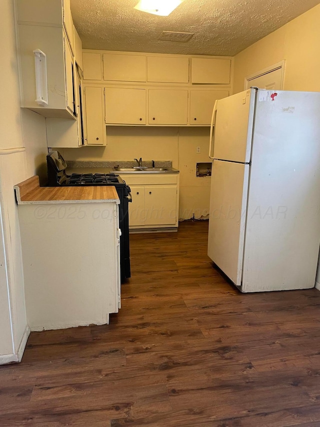 kitchen featuring black gas range, white cabinetry, a sink, and freestanding refrigerator