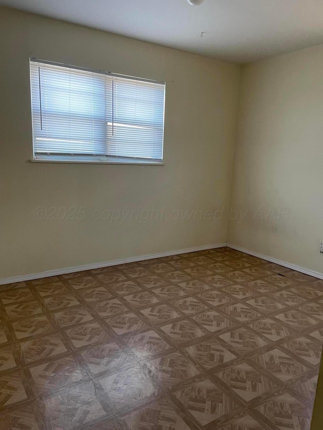 unfurnished room with baseboards