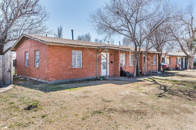 ranch-style home with brick siding, fence, and a front yard