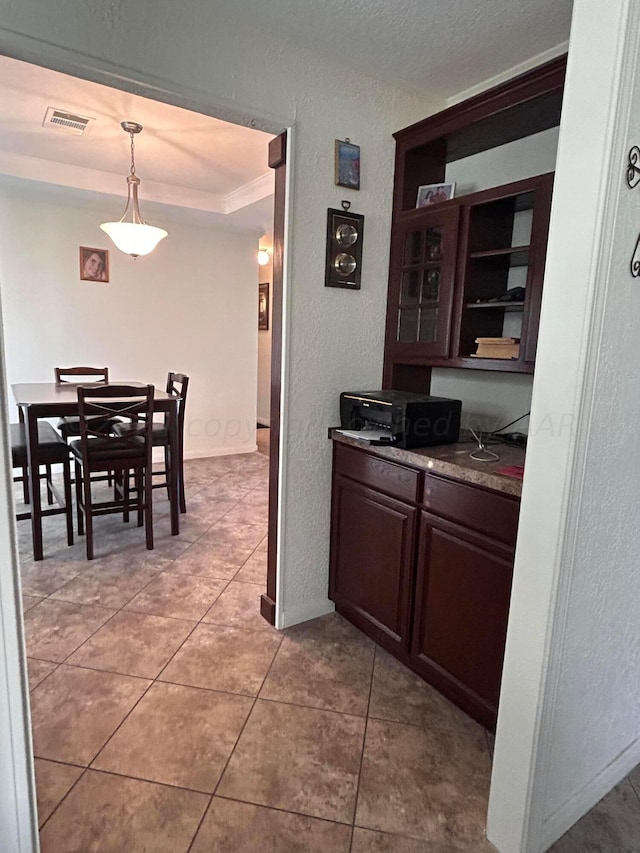 kitchen featuring dark brown cabinetry, hanging light fixtures, and light tile patterned flooring