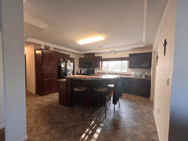 kitchen featuring black appliances, ornamental molding, dark brown cabinetry, a breakfast bar area, and a center island